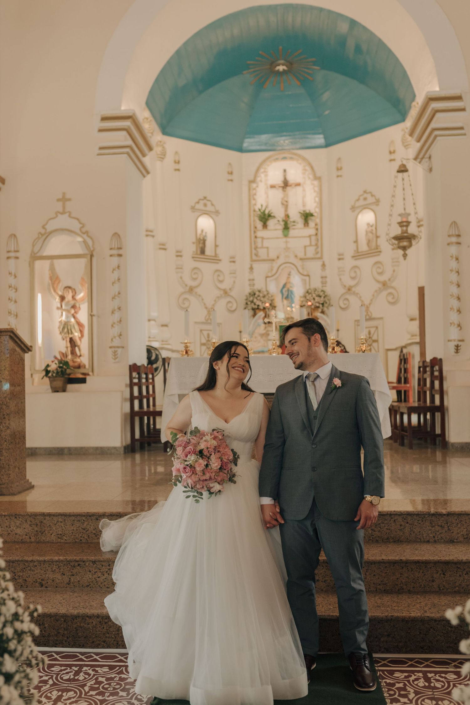 Newlyweds stand together in beautiful church with blue domed ceiling and ornate altar.