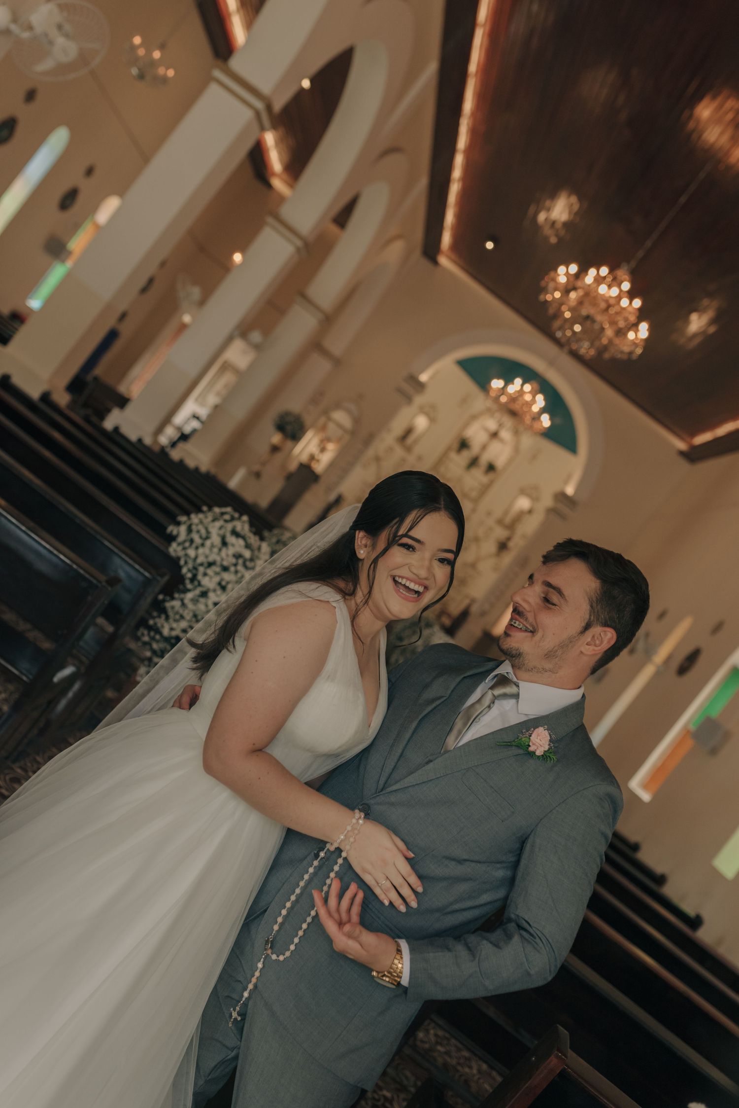 Candid moment of laughter between newlyweds in an elegant church interior.