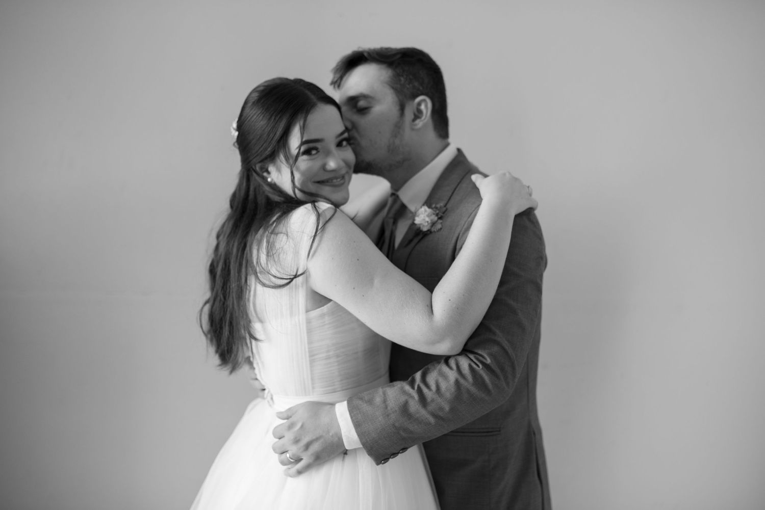 Black and white portrait of embracing newlyweds sharing tender moment.