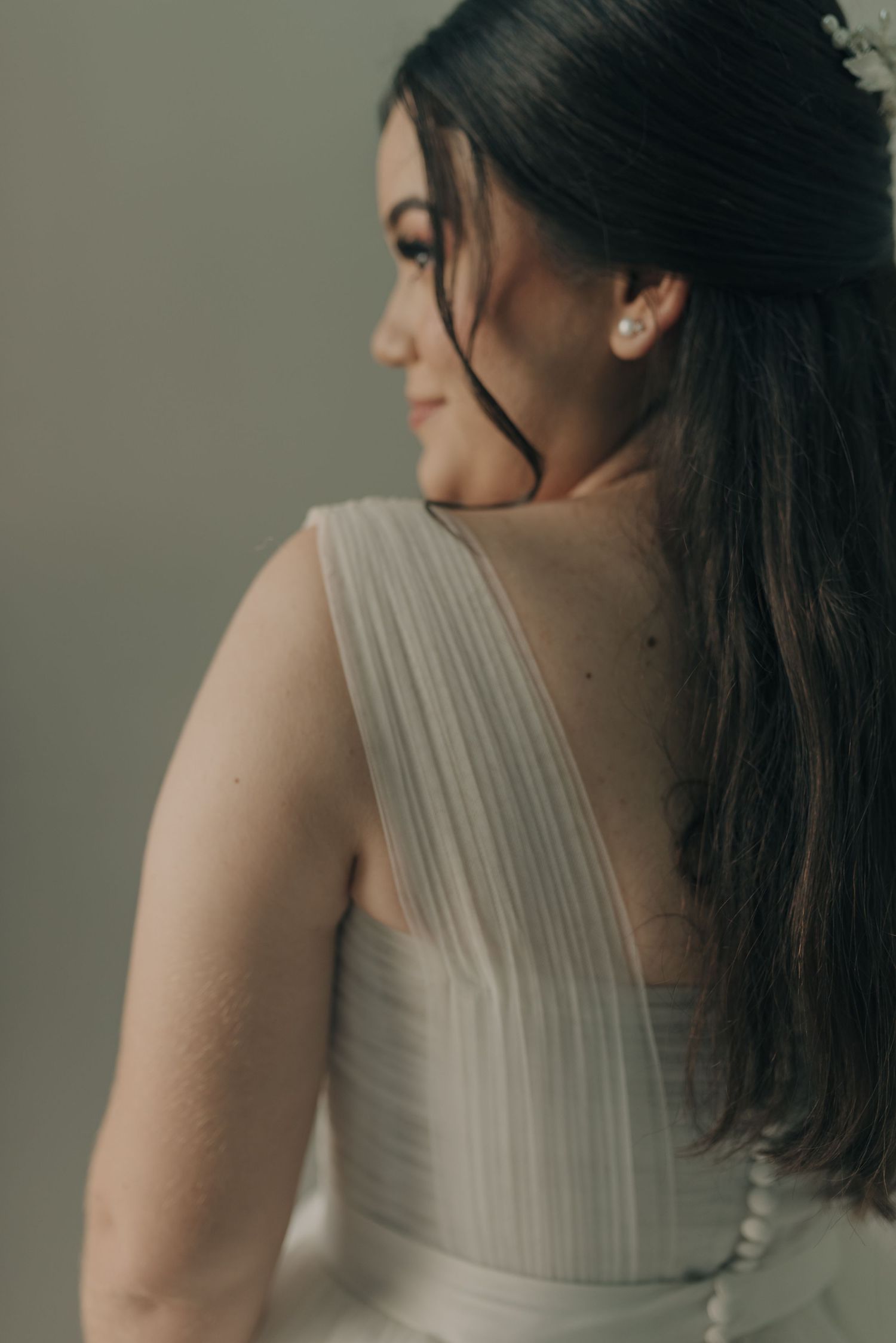 Close-up profile view capturing delicate details of a white bridal gown and flowing dark hair.