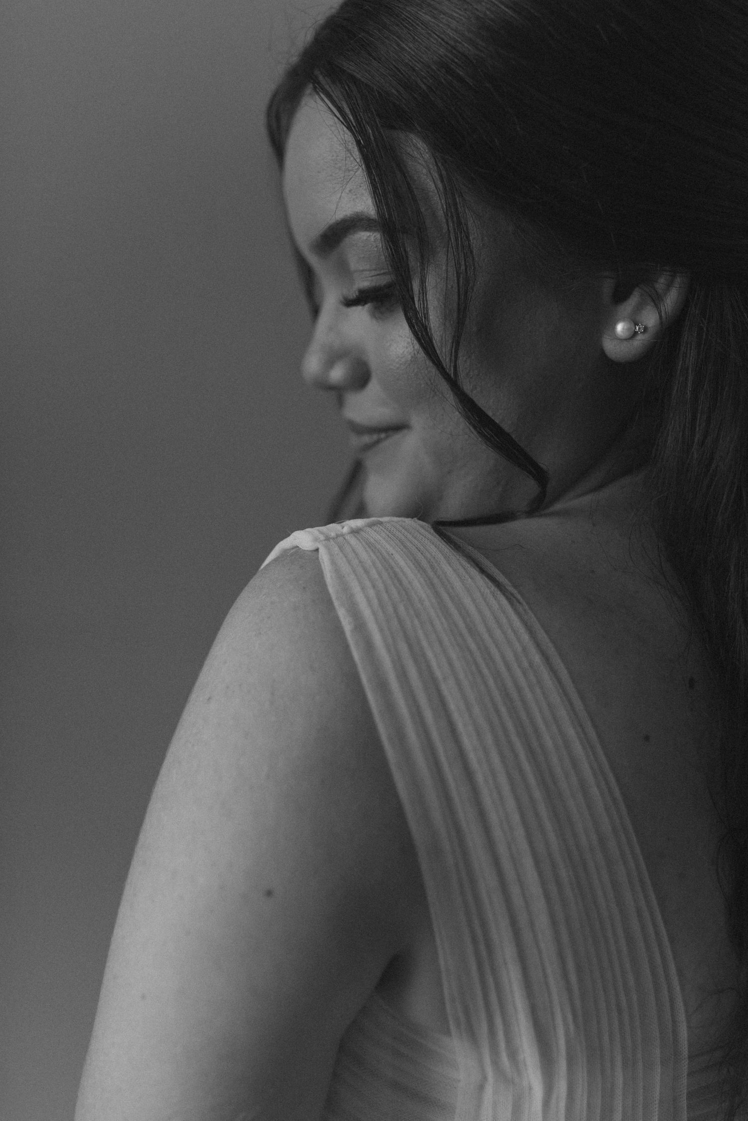 Black and white portrait showing elegant pleated fabric details and a gentle smile.