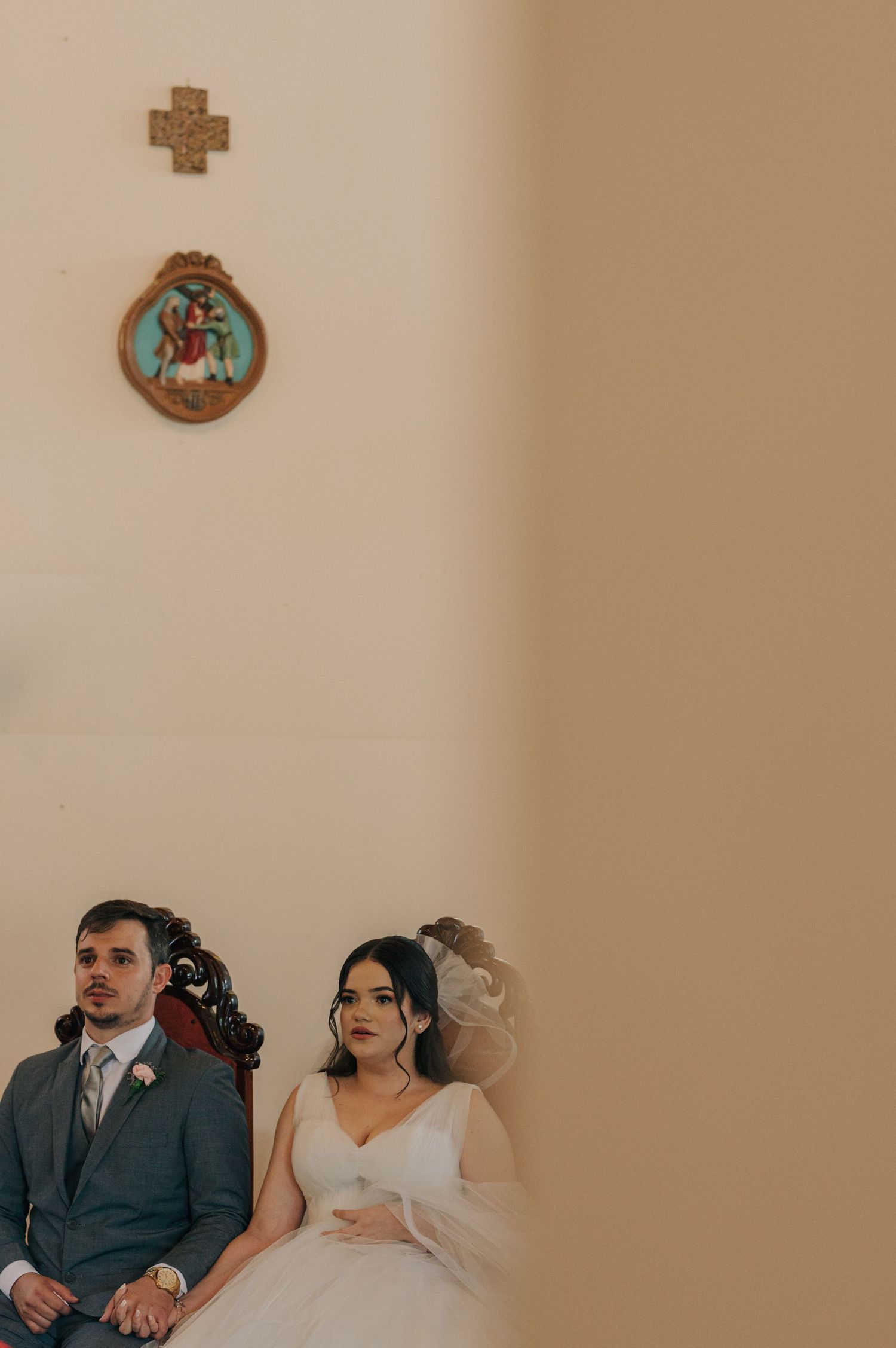 Wedding ceremony scene in a church with religious artwork and crosses on the wall.