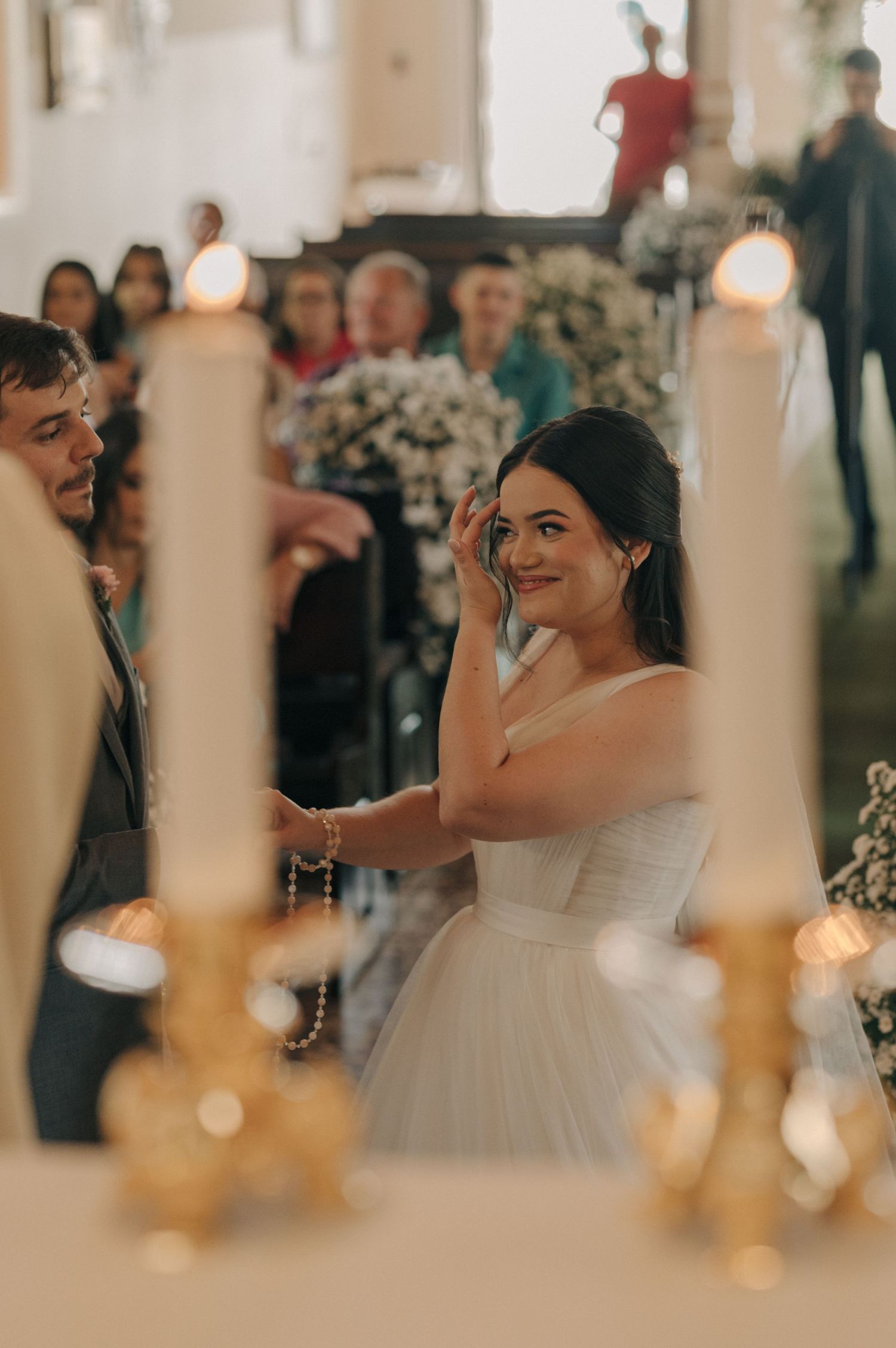Candid wedding moment captured through glowing candles in an elegantly decorated venue.