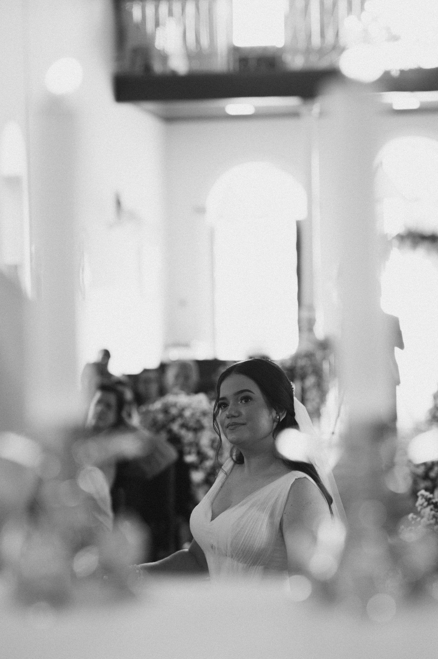 Black and white image of a bride surrounded by soft bokeh lights in a church setting.