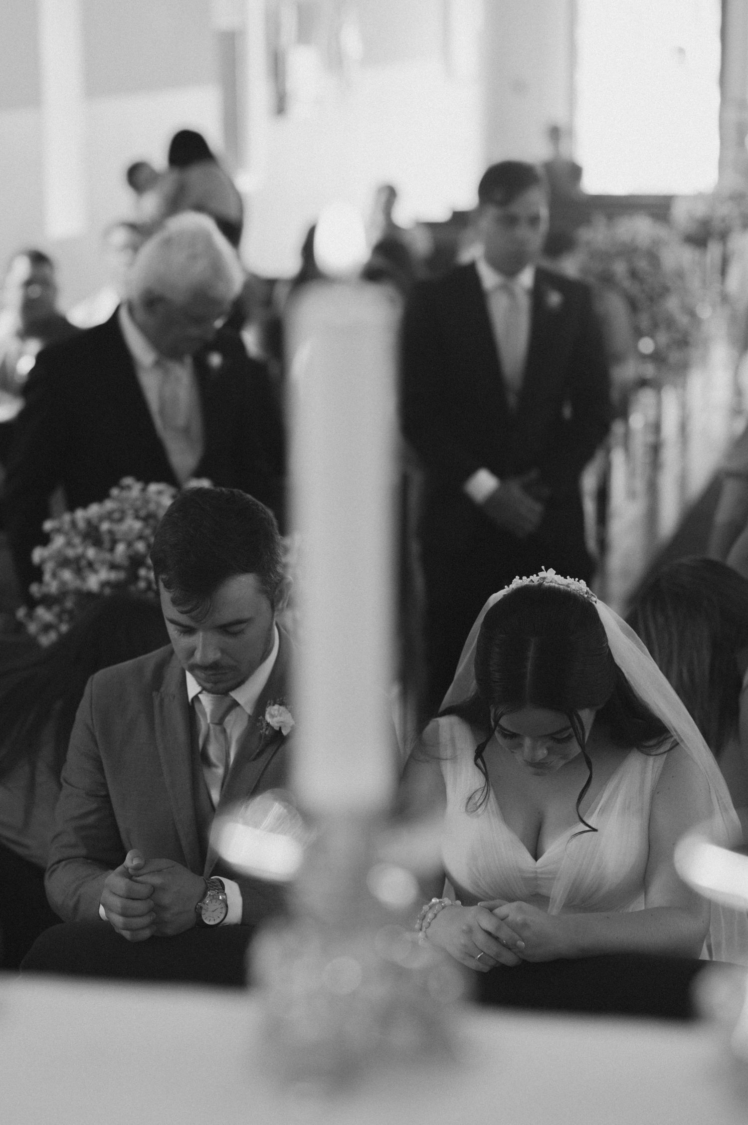 Black and white photograph of a solemn moment during a traditional church wedding ceremony.