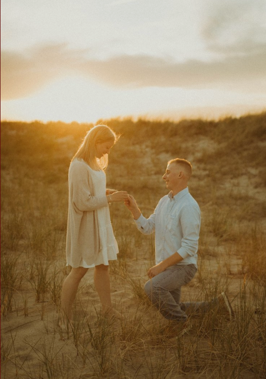 A couple shares a tender moment at sunset in a desert landscape as someone proposes marriage.