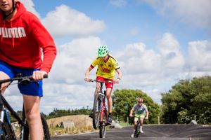 Cyclists riding mountain bikes on rural road against blue sky.