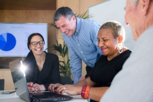 Business colleagues collaborating on laptop computer during casual office meeting.