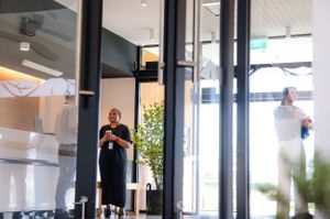 Person standing in modern office building lobby with glass walls and natural light.