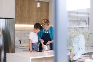 Two people cooking together in a modern kitchen with wood accents and stainless steel appliances.