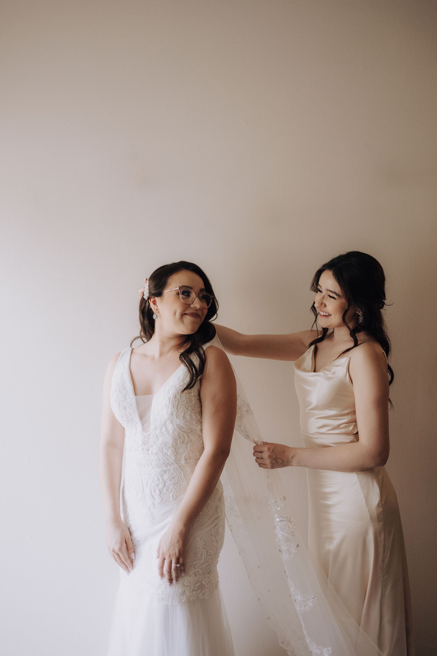 Two people share a candid moment while getting ready in formal wedding attire.
