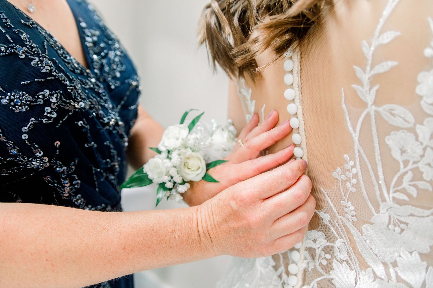Close-up details of intricate white lace embroidery on wedding dress.