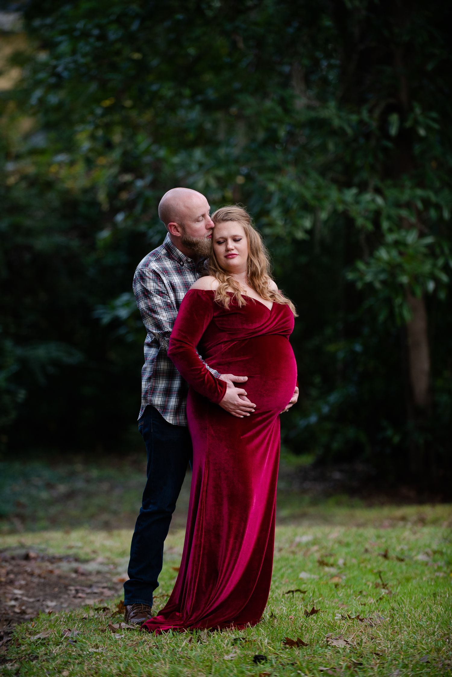 Expecting couple in casual attire poses together outdoors in autumn.