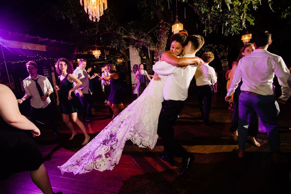 Wedding reception dance floor with chandelier lighting and lively dancing.