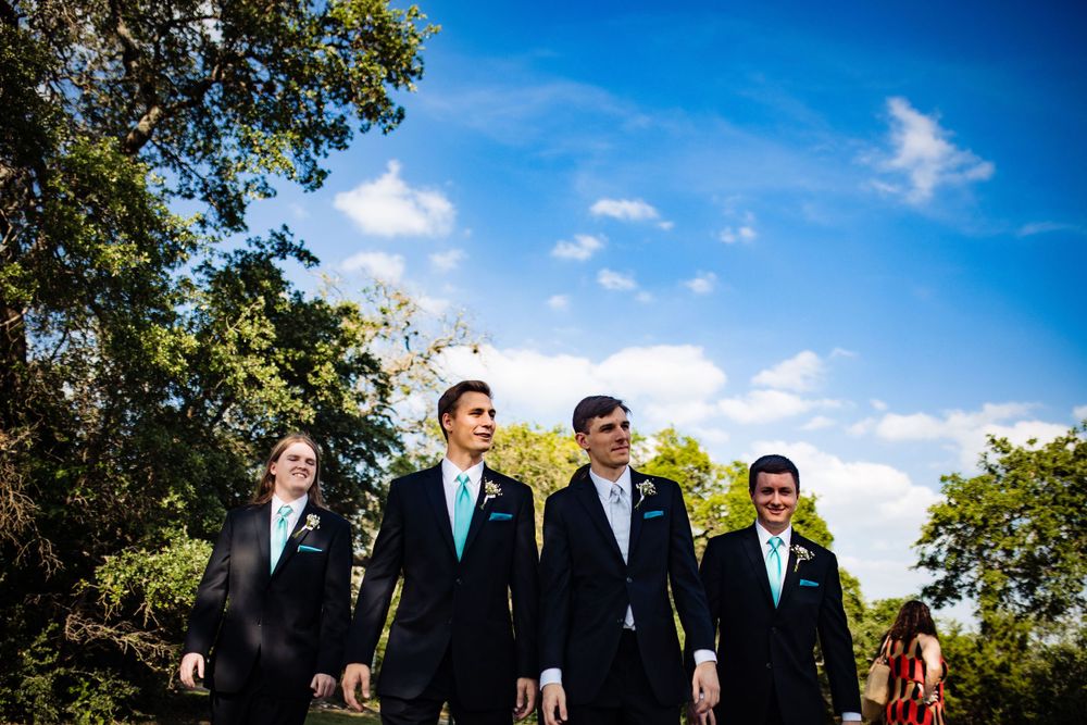 Groomsmen walking together on a sunny day with blue skies and trees in background.