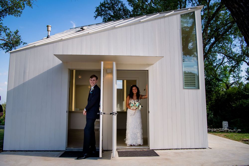 A modern white chapel entrance with figures waiting in doorway.