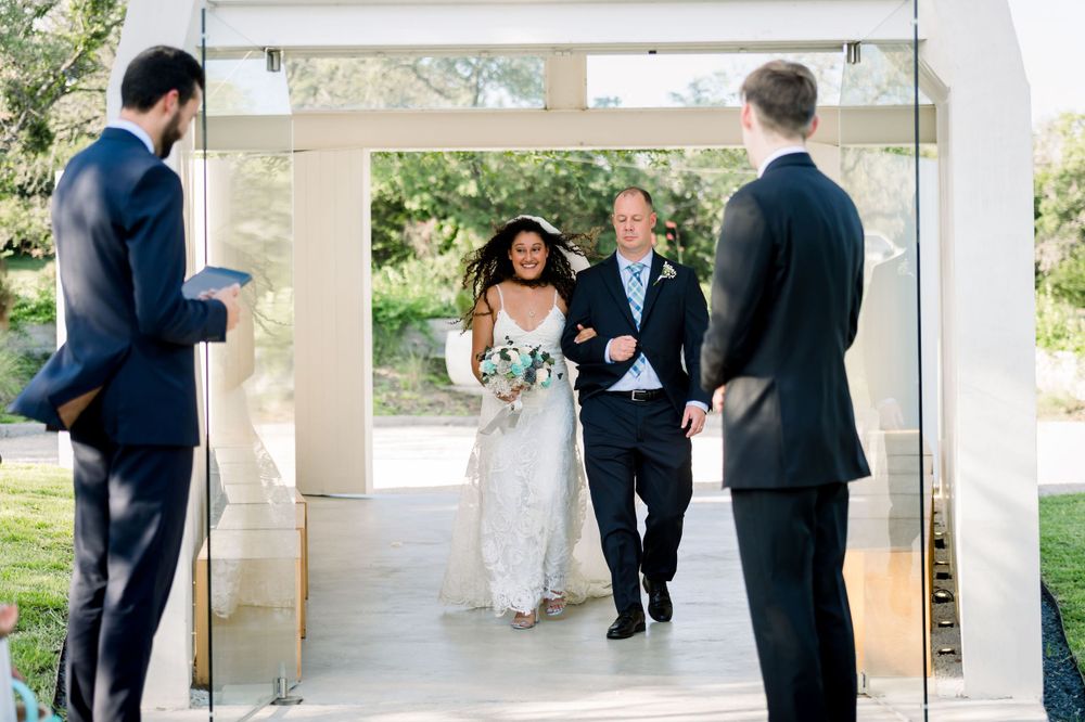A processional entrance through modern glass doors at an outdoor venue.