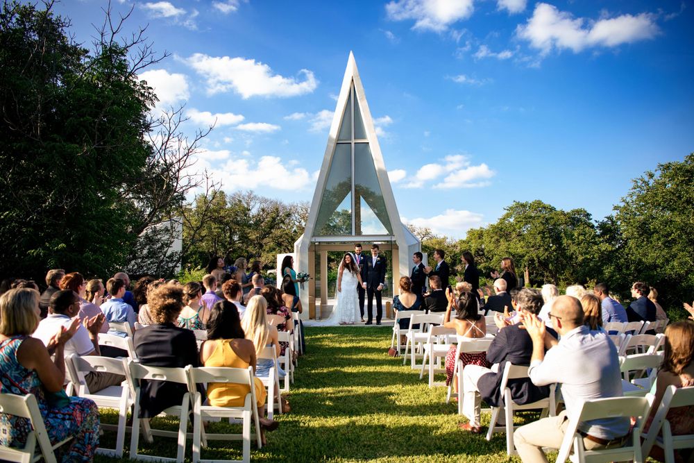 Modern white chapel wedding ceremony with guests seated outdoors under blue skies.