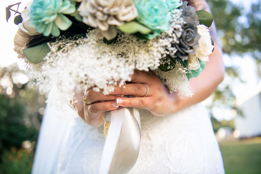 Close up view of a bridal bouquet with mint green succulents, white flowers and delicate ribbons.