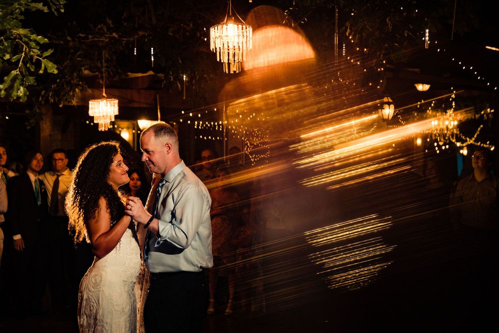 Artistic nighttime wedding portrait with ethereal light streaks and chandeliers.