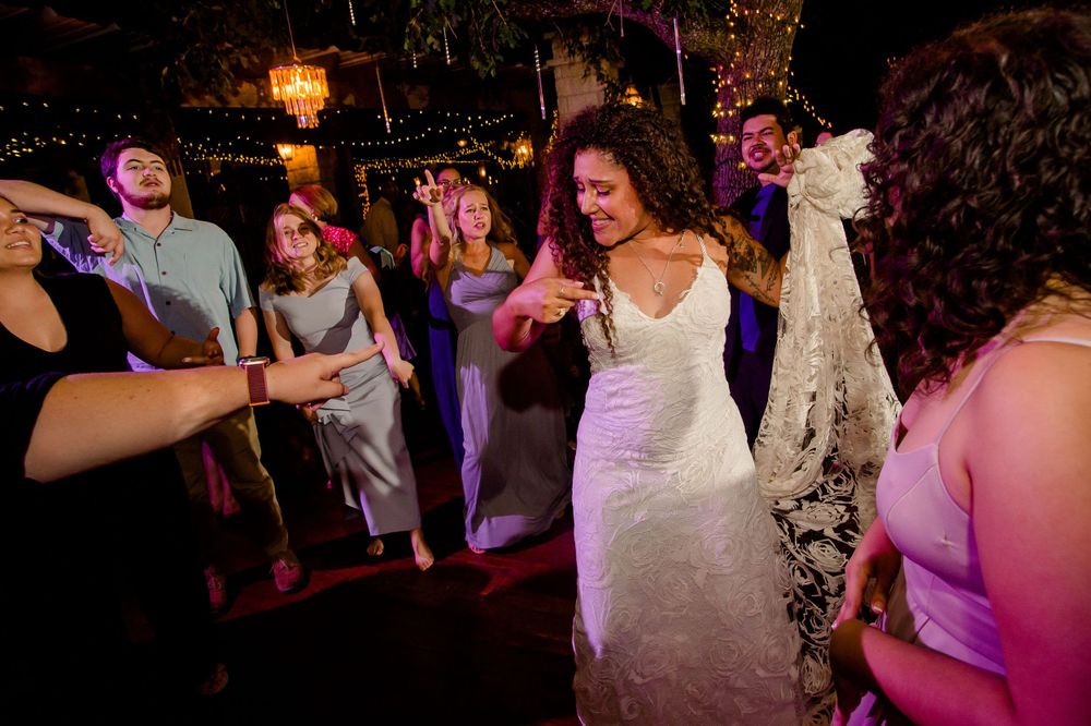A joyful dance scene at a wedding reception with a white dress twirling on the dance floor.