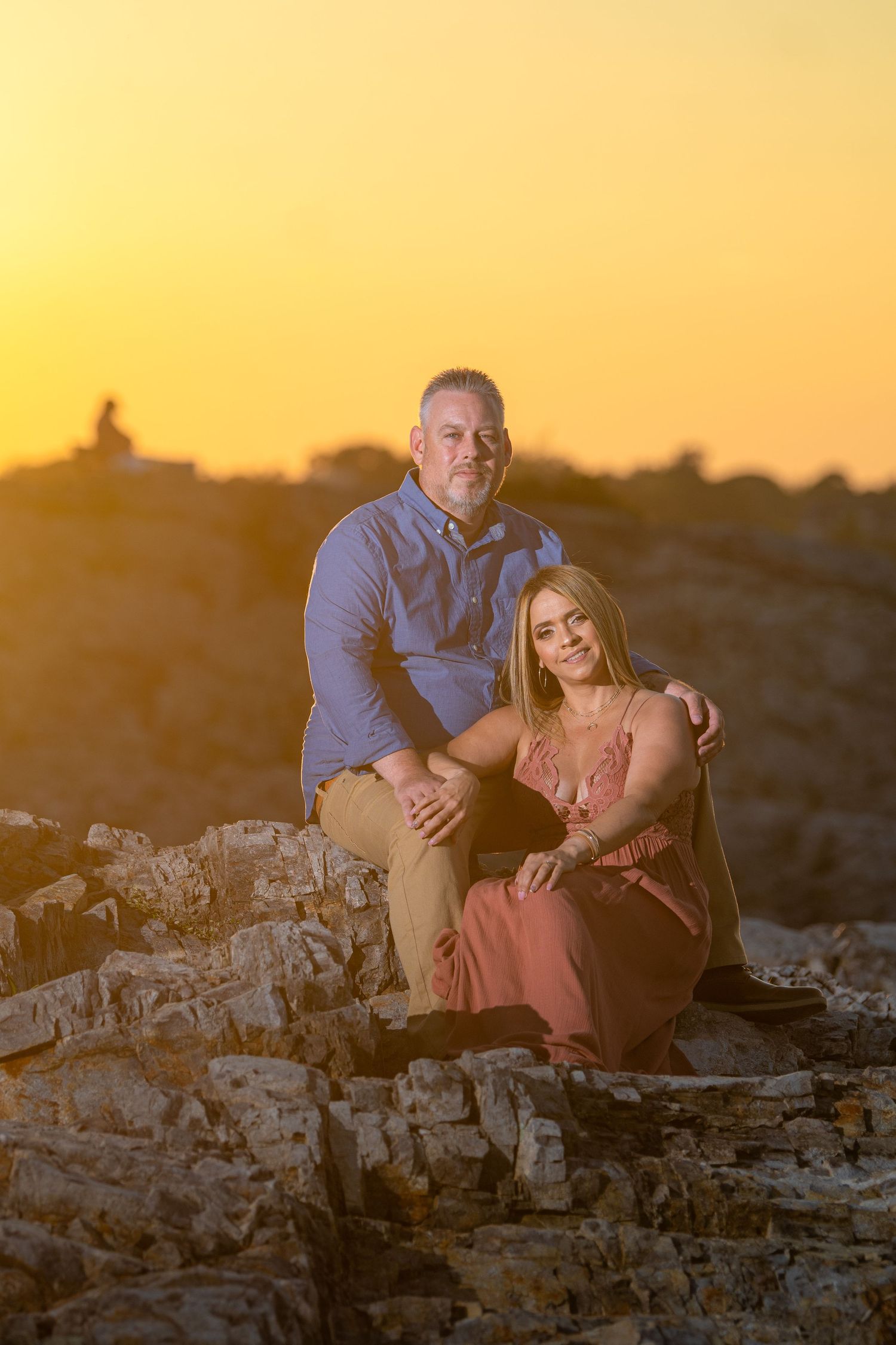 A romantic sunset portrait session on rocky terrain with warm golden lighting.