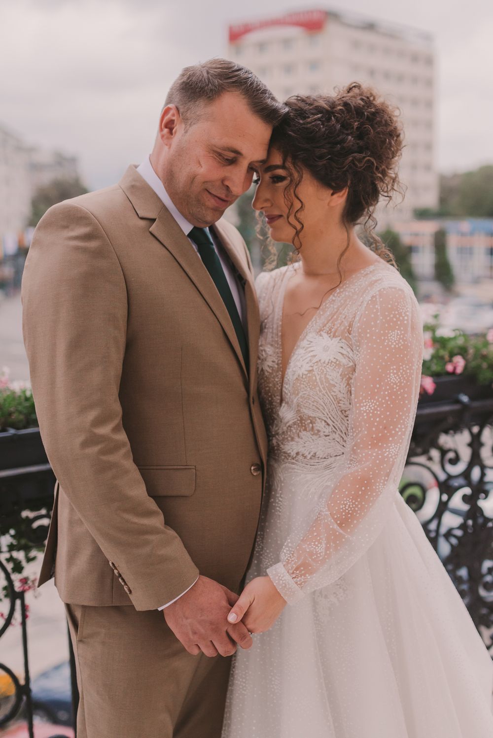 Romantic wedding couple shares an intimate moment while wearing tan suit and lace white dress.