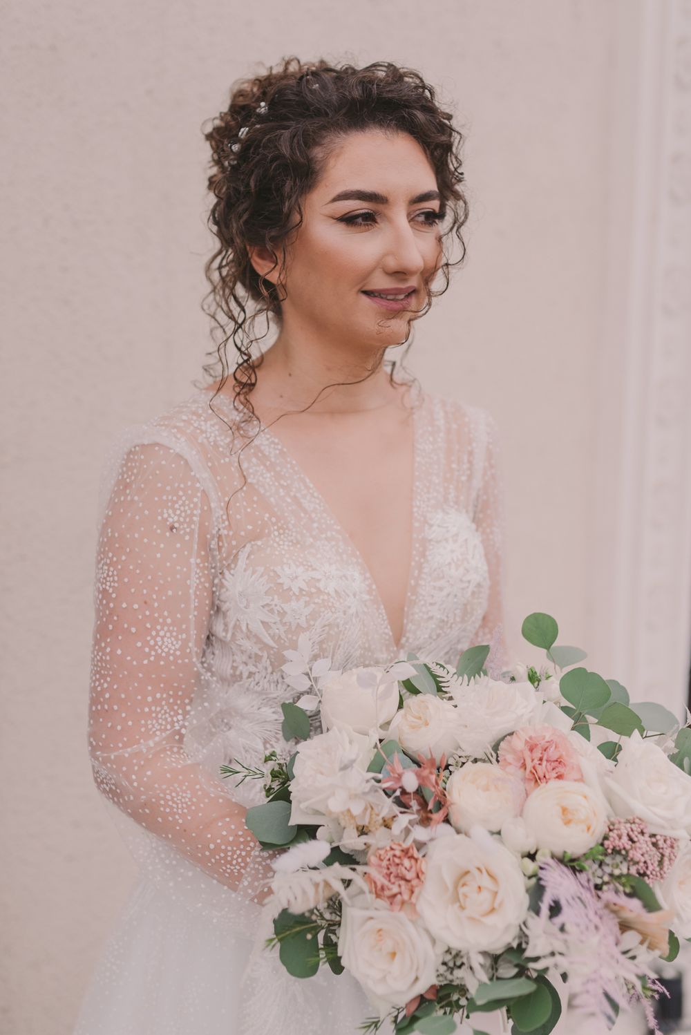 Close-up of bride holding elegant pink and white floral bouquet with eucalyptus accents.