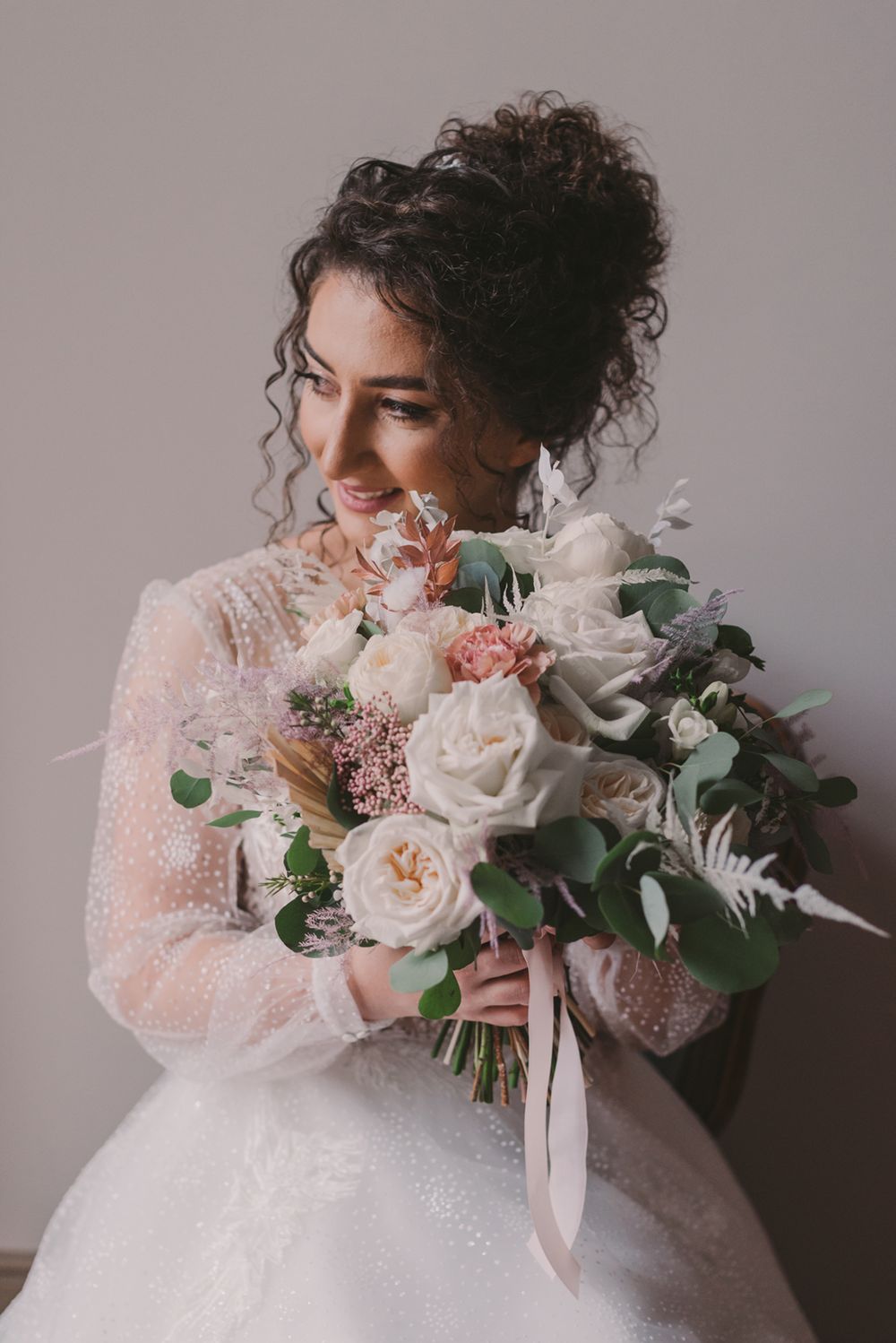 Close-up of bridal bouquet with blush roses, white flowers and delicate greenery.