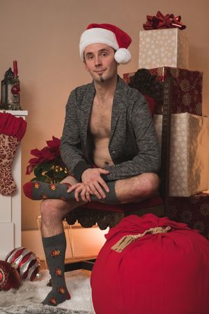 Holiday scene with wrapped presents and person in Santa hat and festive socks.