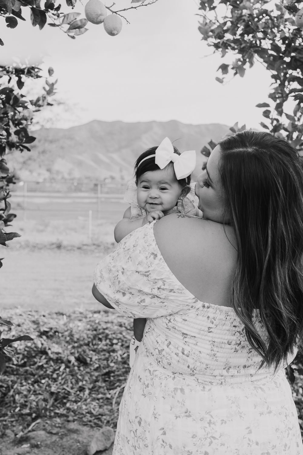 A tender moment between parent and child in a garden with mountains in the background.