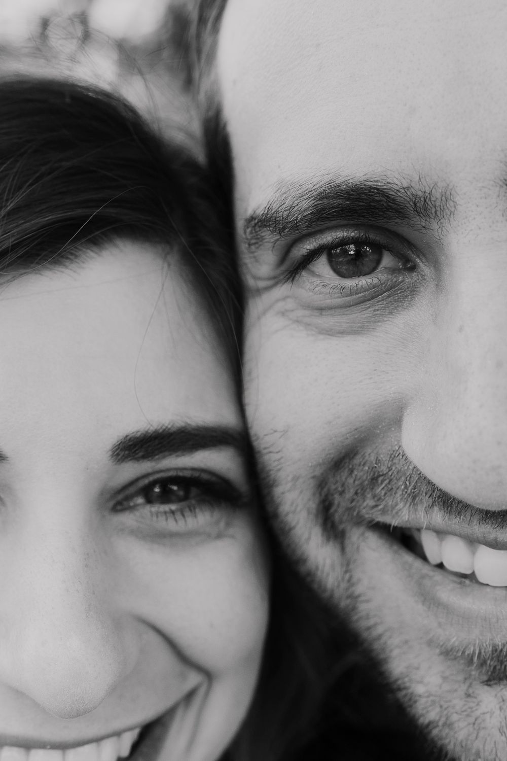 Close-up black and white portrait of a smiling couple's faces.