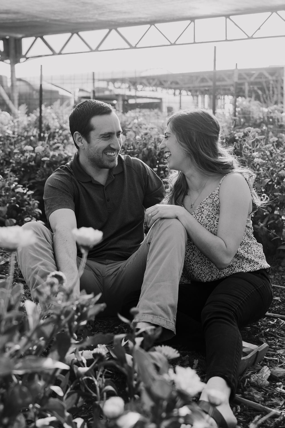 Black and white candid photo of couple sharing joyful moment in garden.