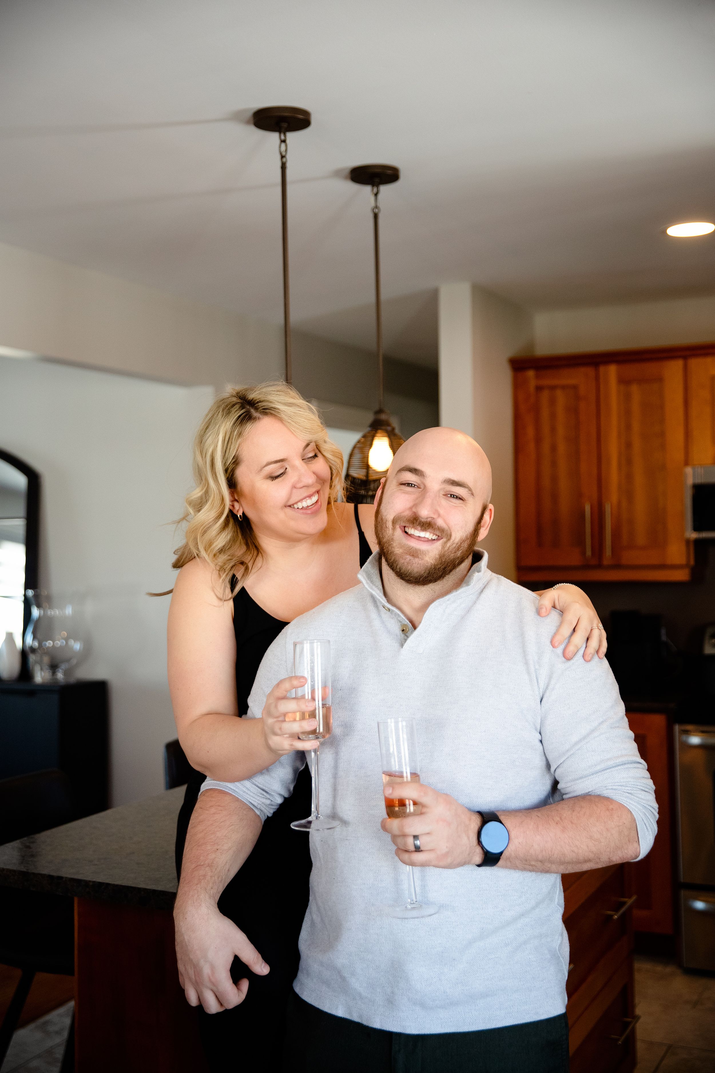 Happy couple sharing drinks and laughter in their kitchen.