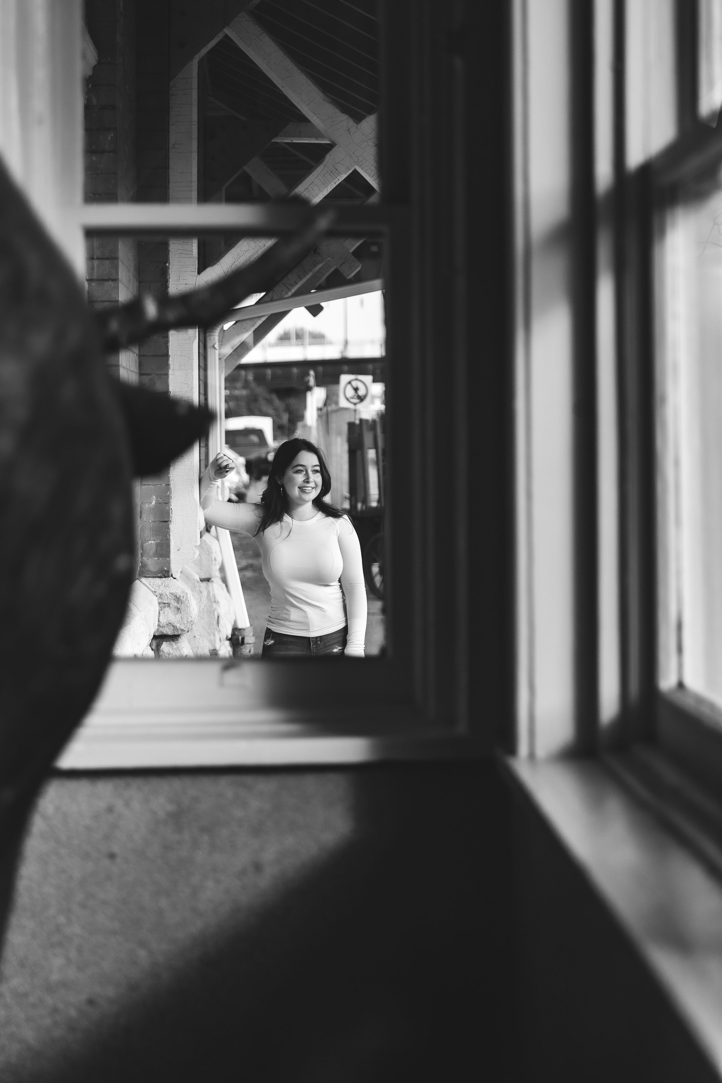 Black and white image of someone viewed through a window frame.