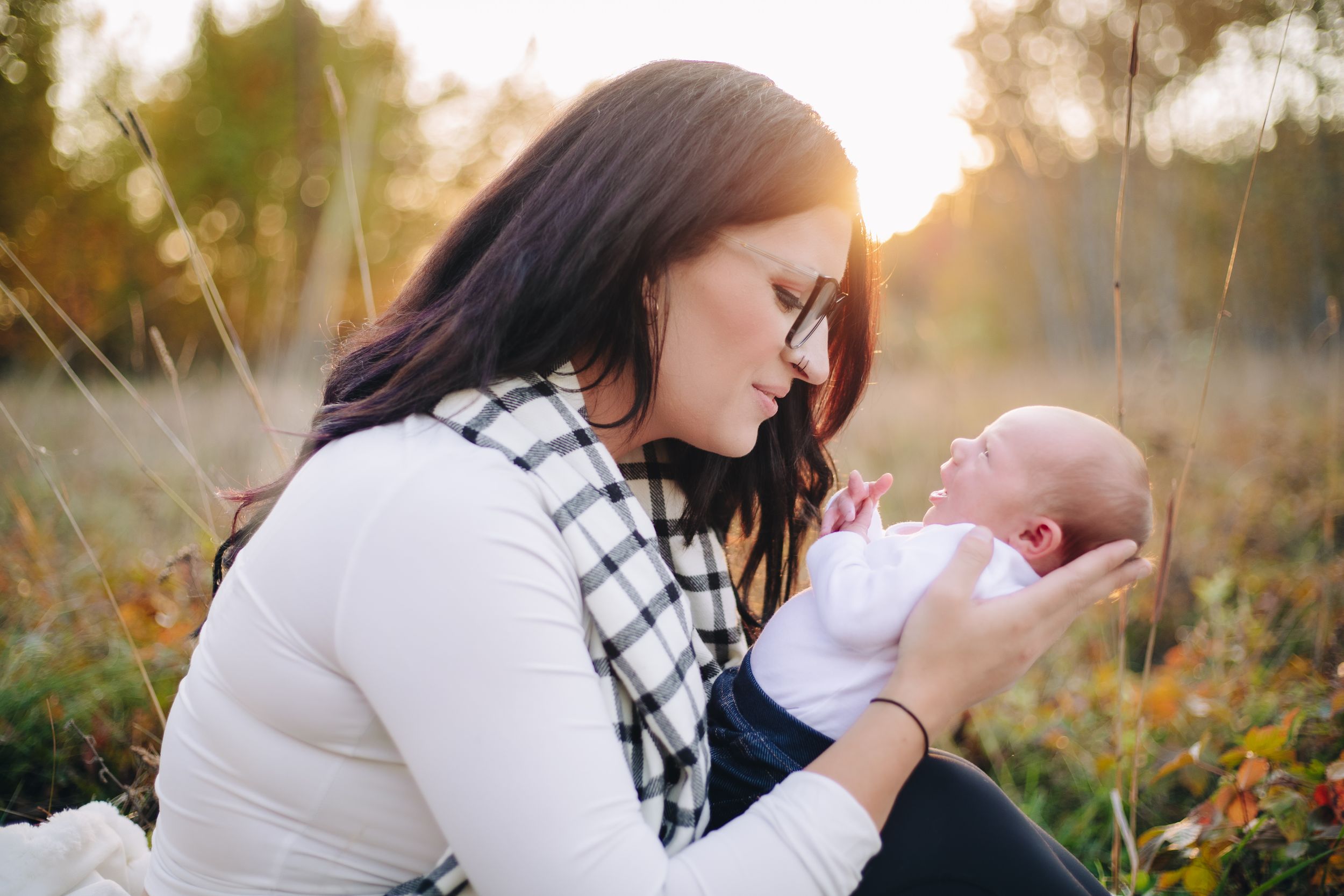 Tender moment between adult and baby during golden hour in a natural outdoor setting.