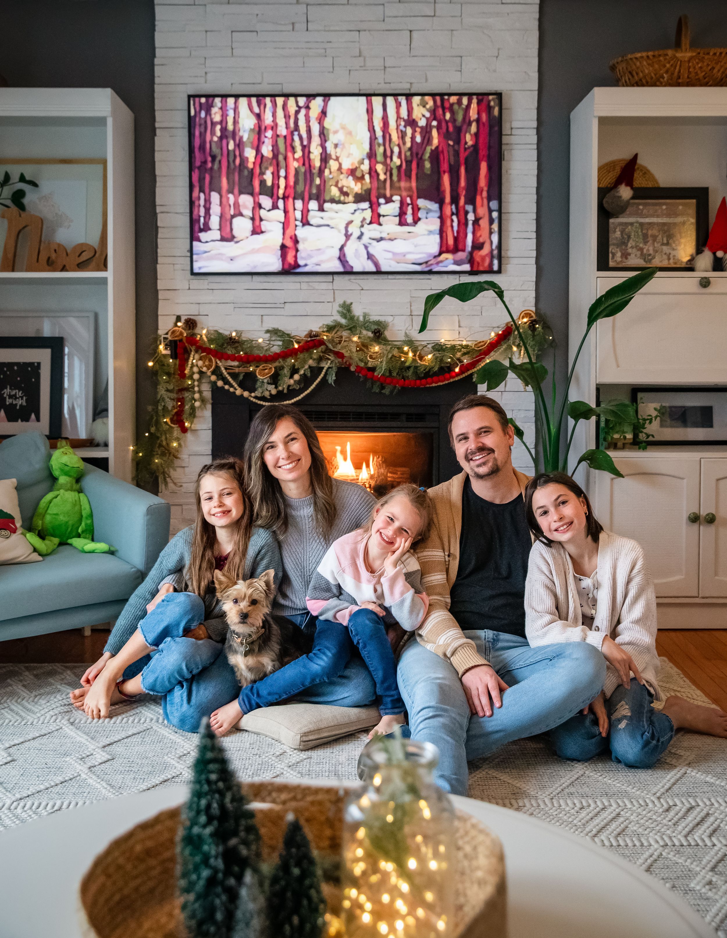 Cozy family holiday scene with Christmas decorations, a fireplace, and a dog.