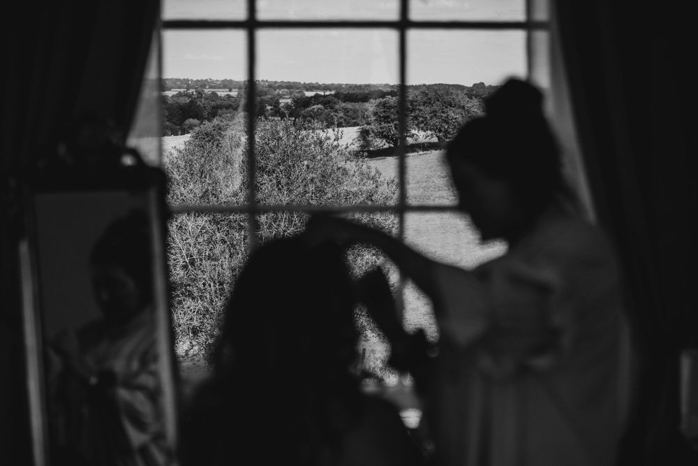 Silhouette figures by window during wedding preparation with scenic view.
