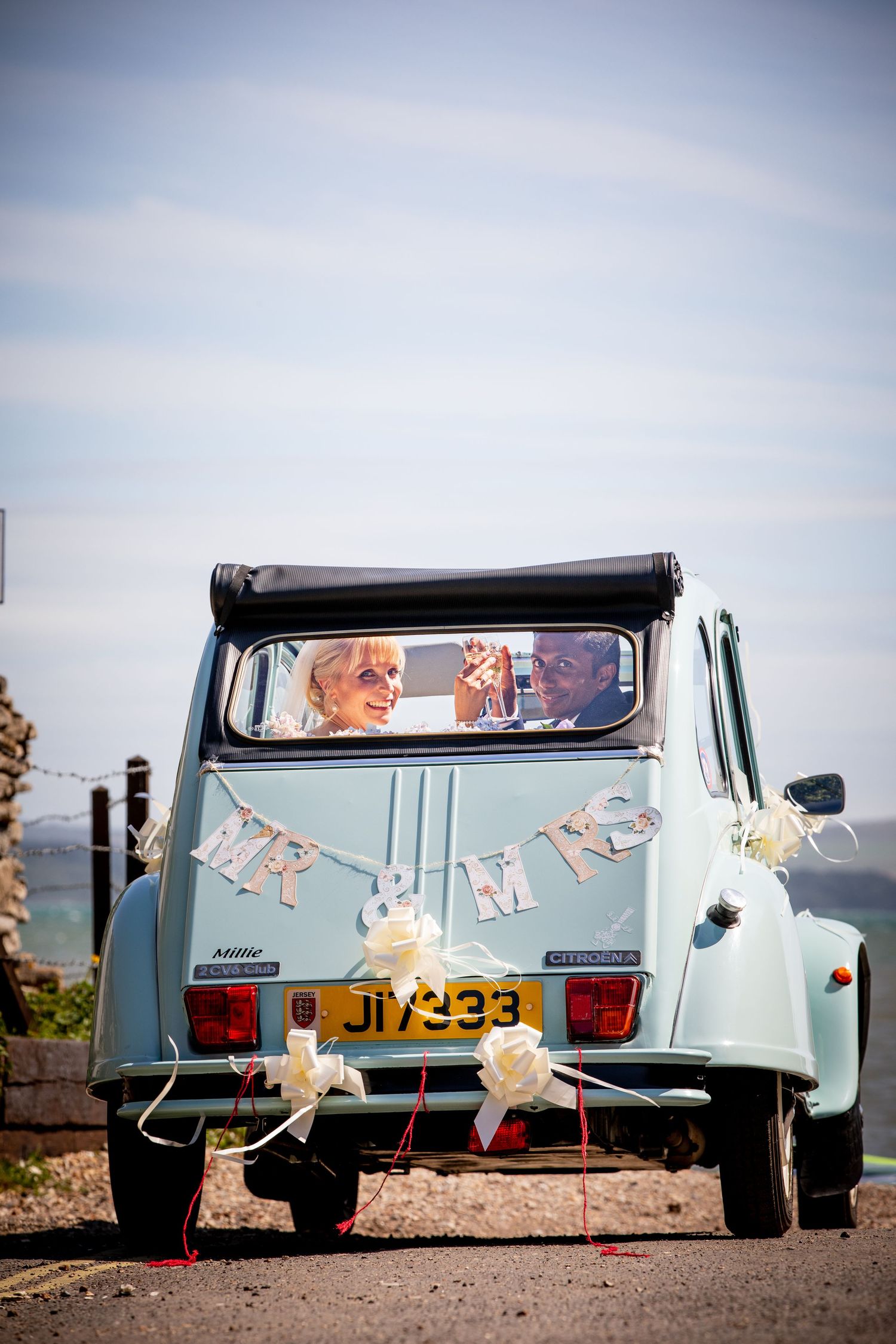 Light blue vintage car decorated with wedding ornaments photographed from different angles.