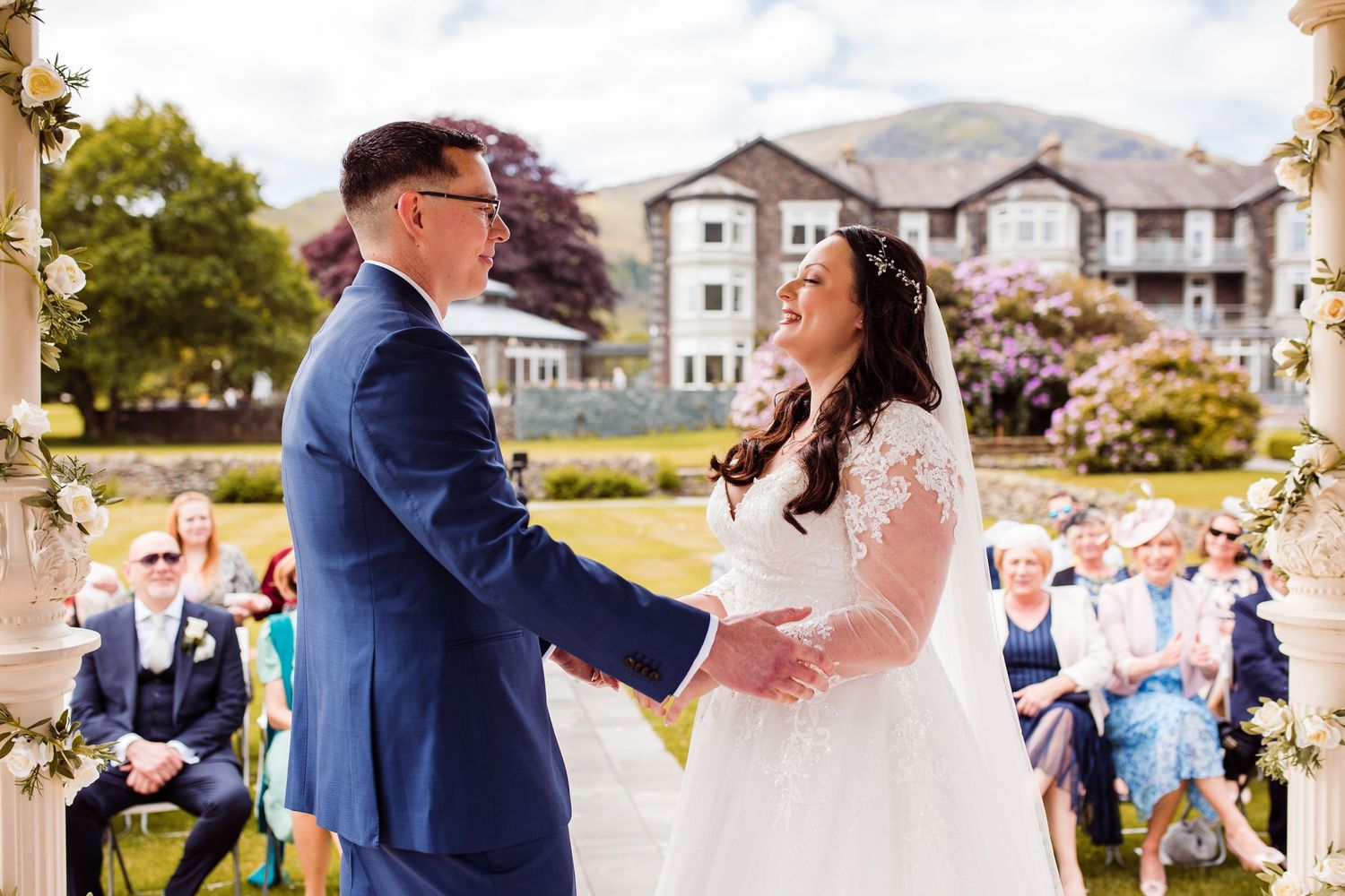 Wedding ceremony taking place on a lush lawn with mountain backdrop and elegant decor.