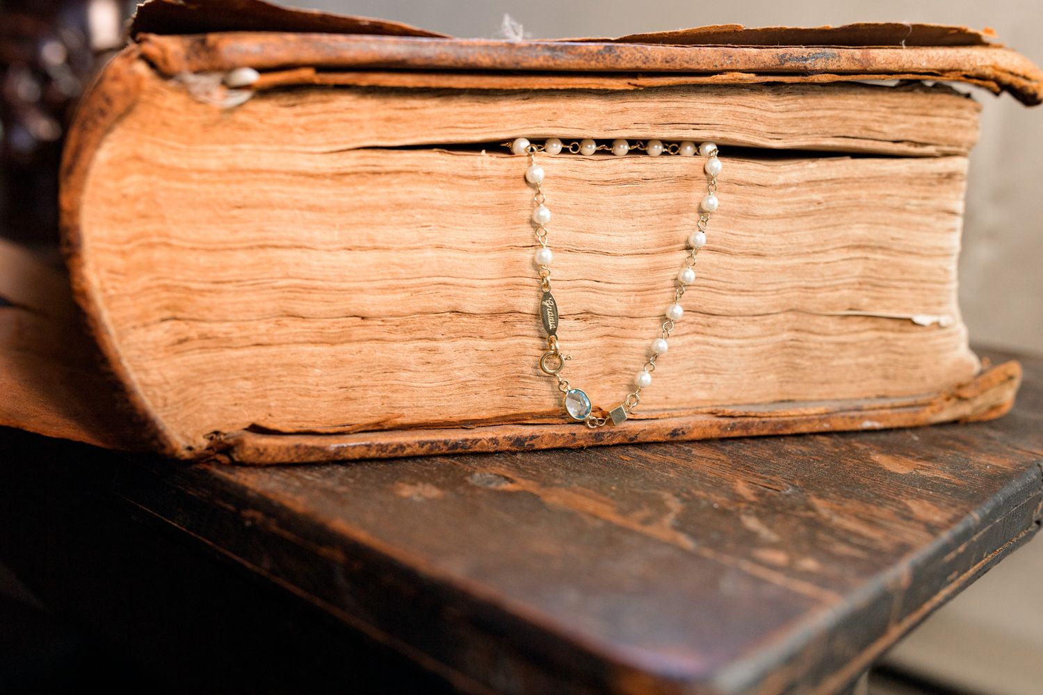 Pearl necklace draped across weathered pages of an old book.