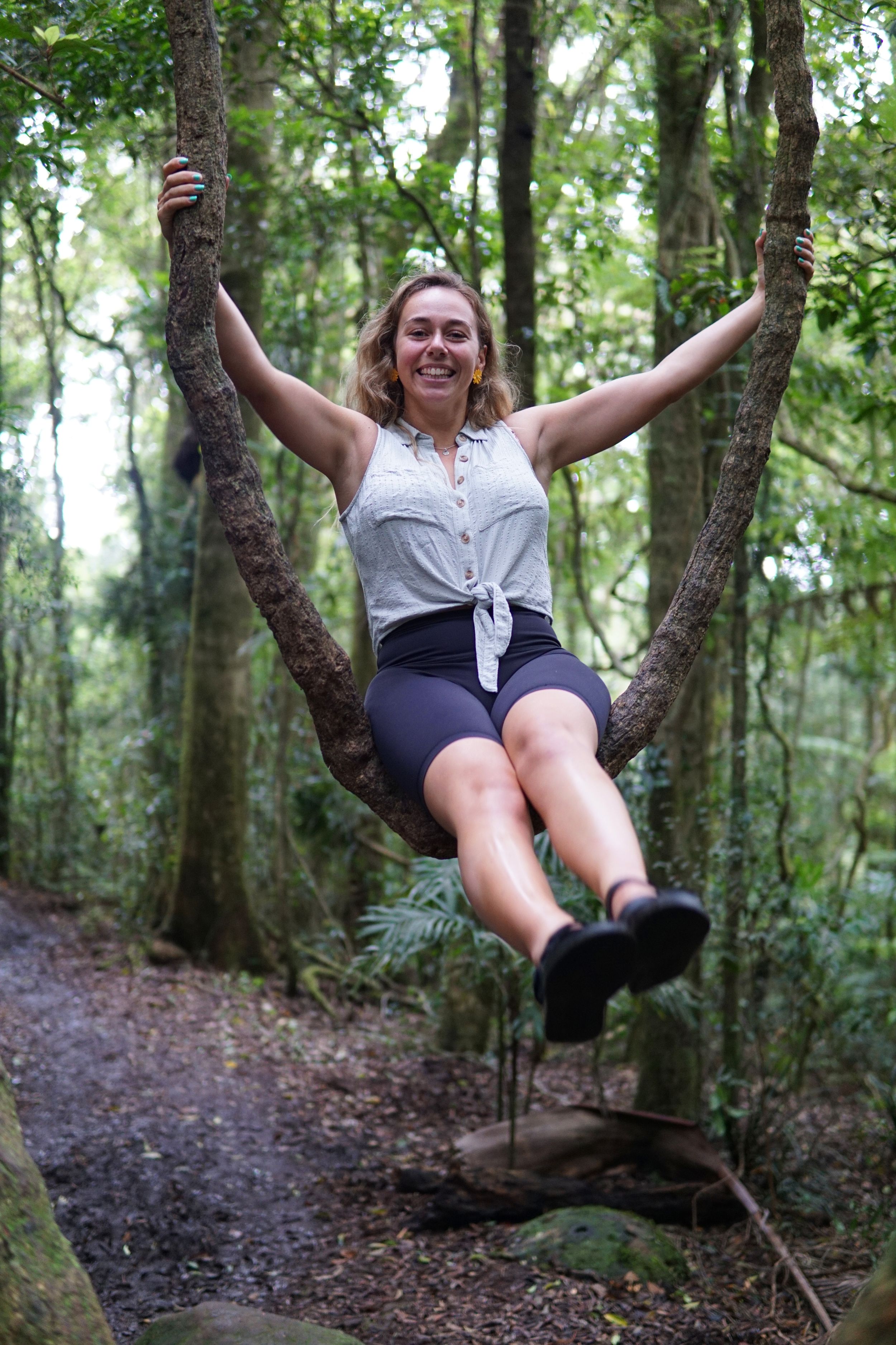 Adventurous pose hanging between trees on a forest path.