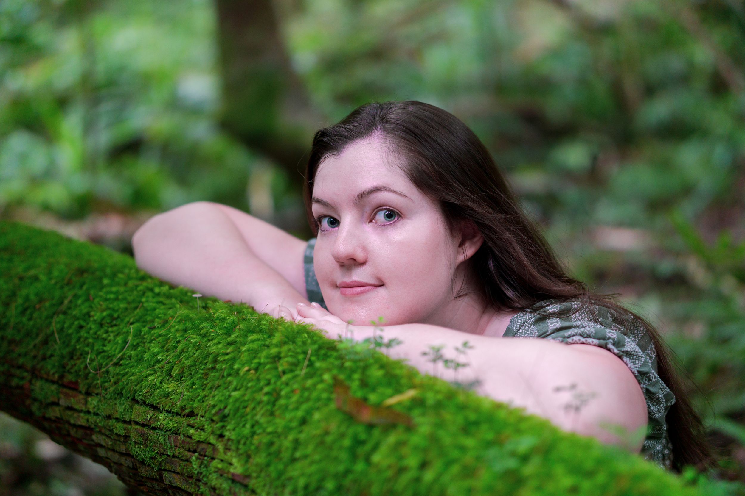 Dreamy forest portrait resting on moss-covered log.