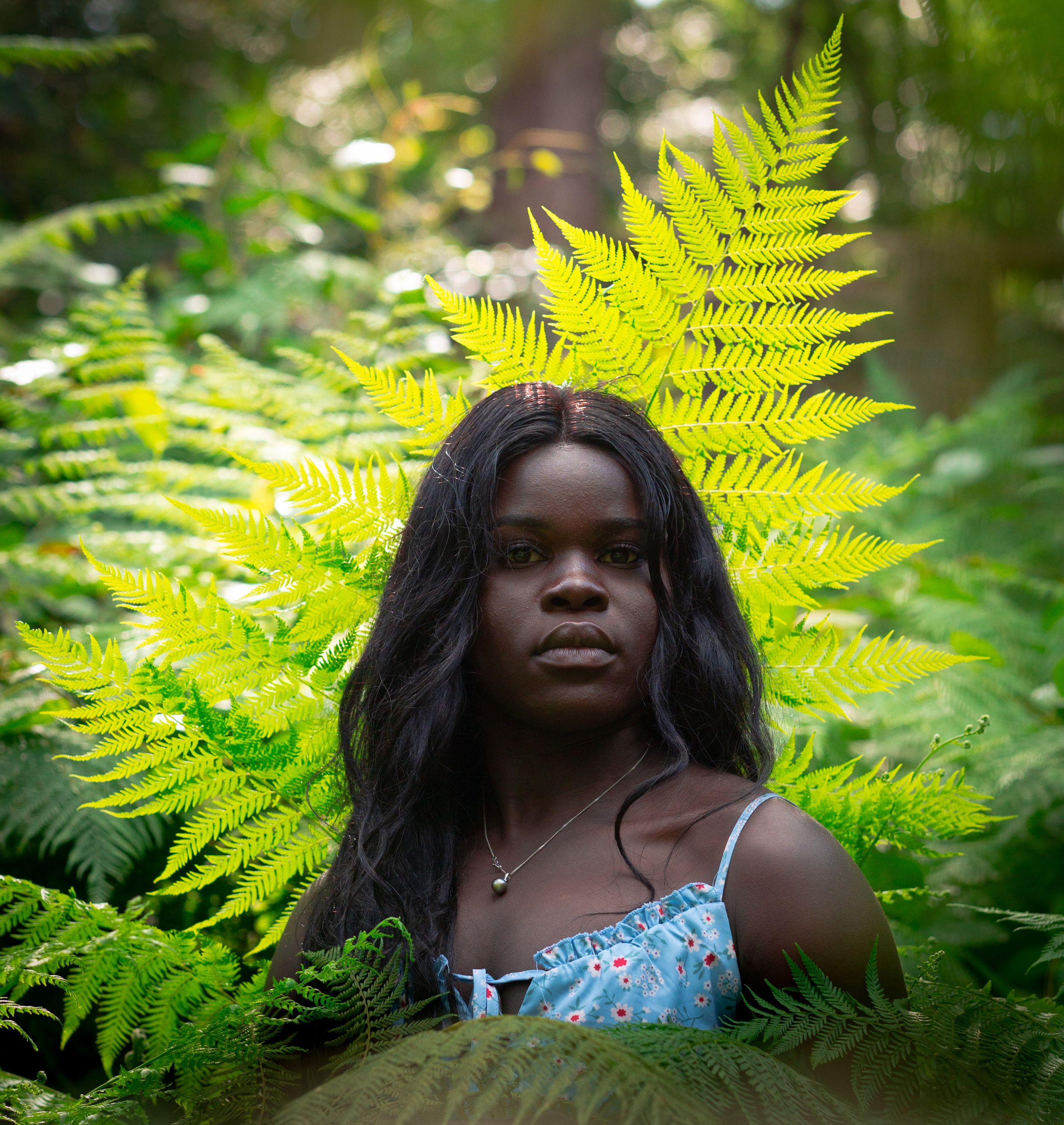 Portrait among vibrant green ferns in a lush forest setting.
