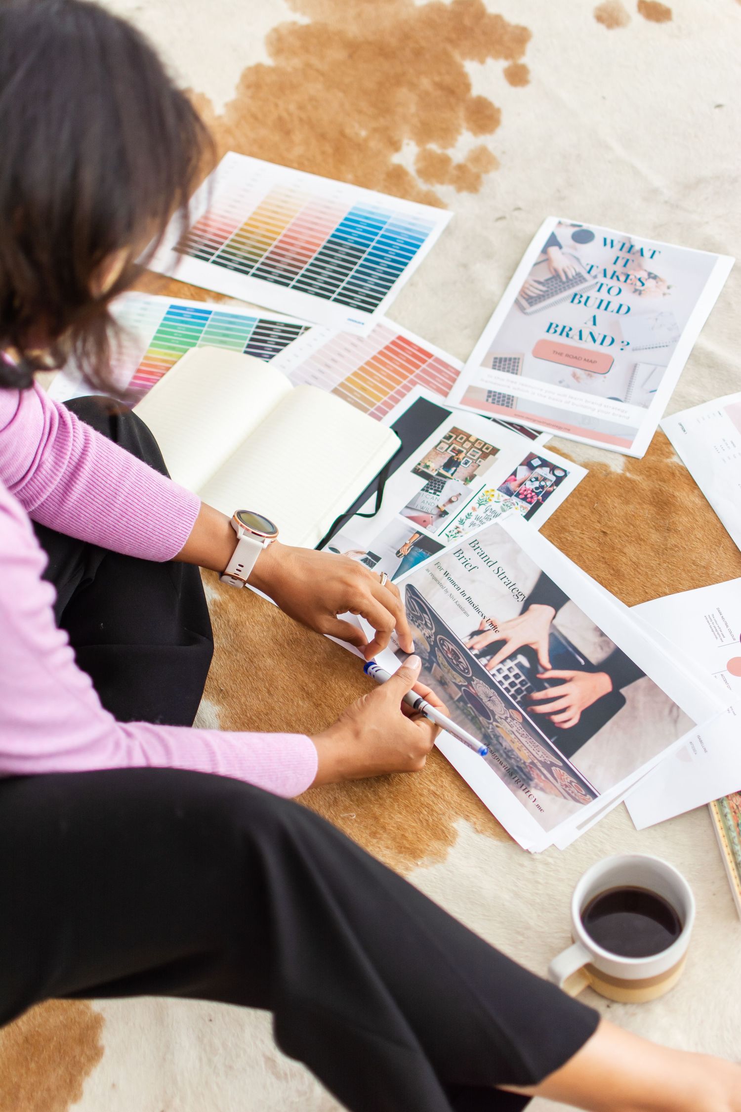Designer reviewing color swatches and project materials with coffee on wooden table.