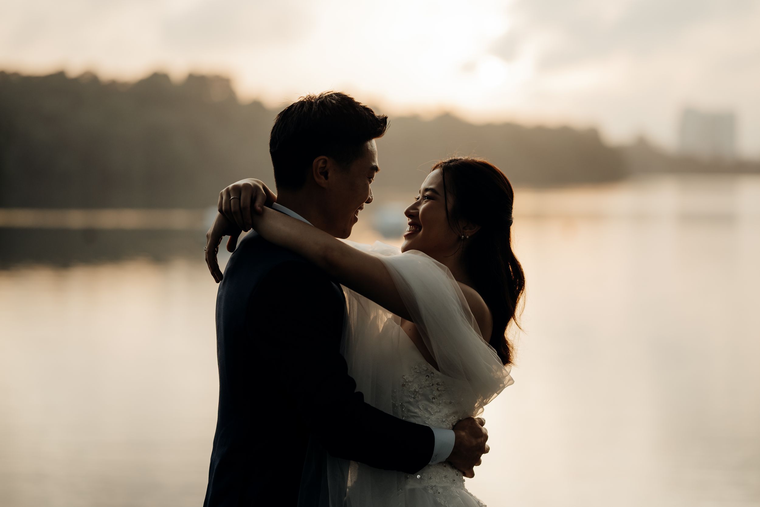 Intimate couple pose while the sun is coming out of the horizon in the back