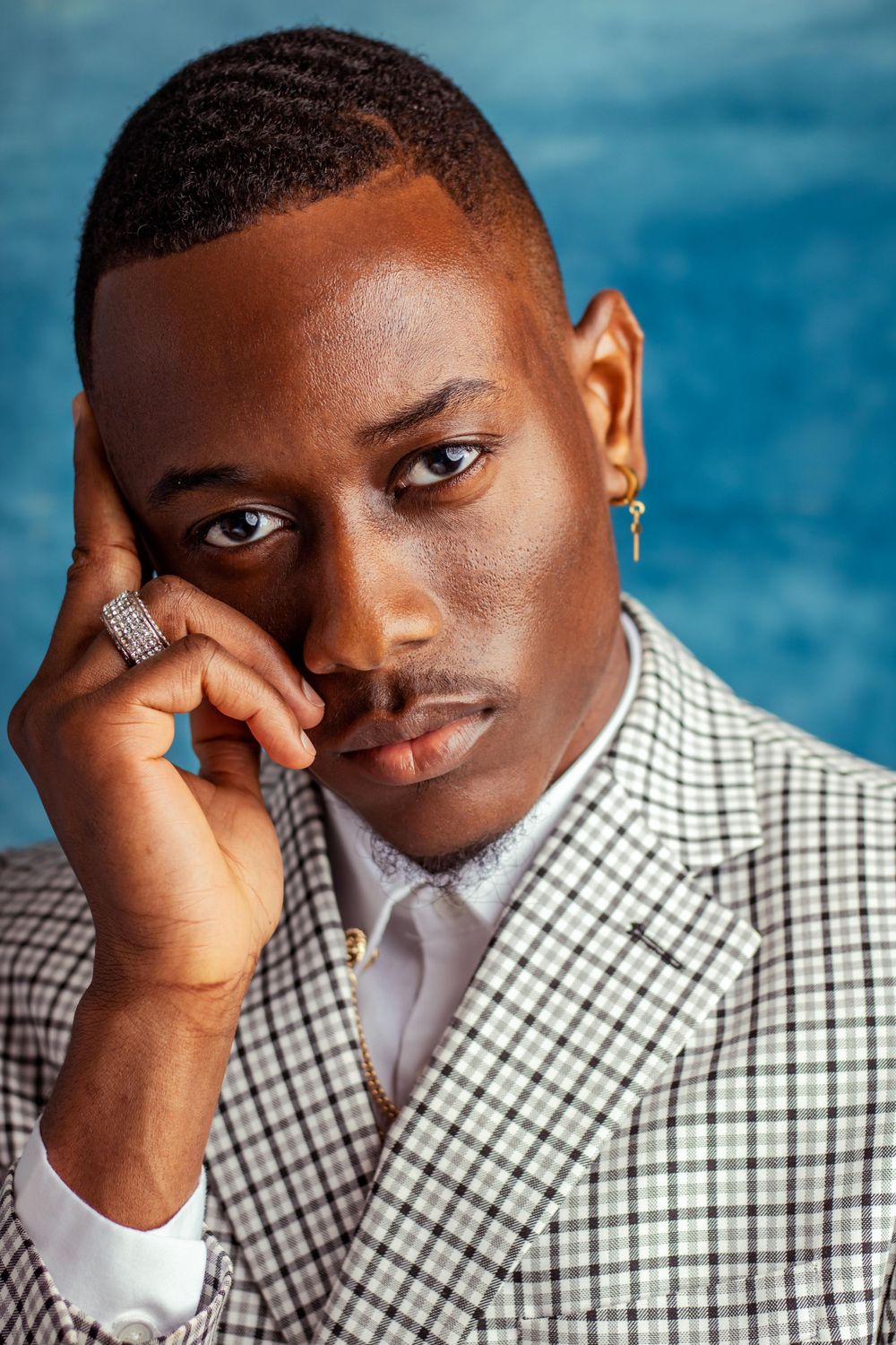 Portrait series showing different poses and expressions against a blue background wearing a checkered shirt.