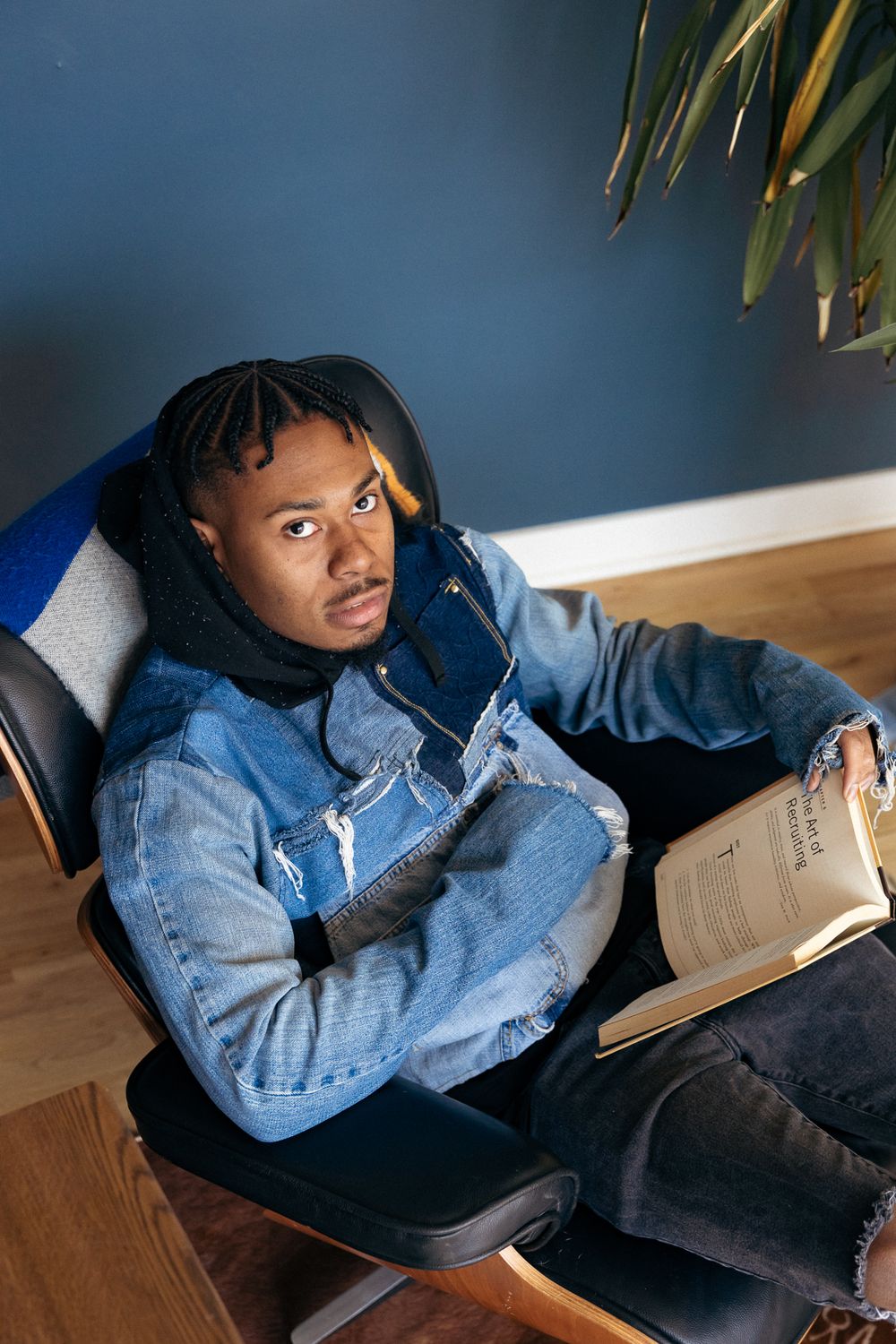 Casual study scene with person in denim jacket reading book while relaxing in chair.