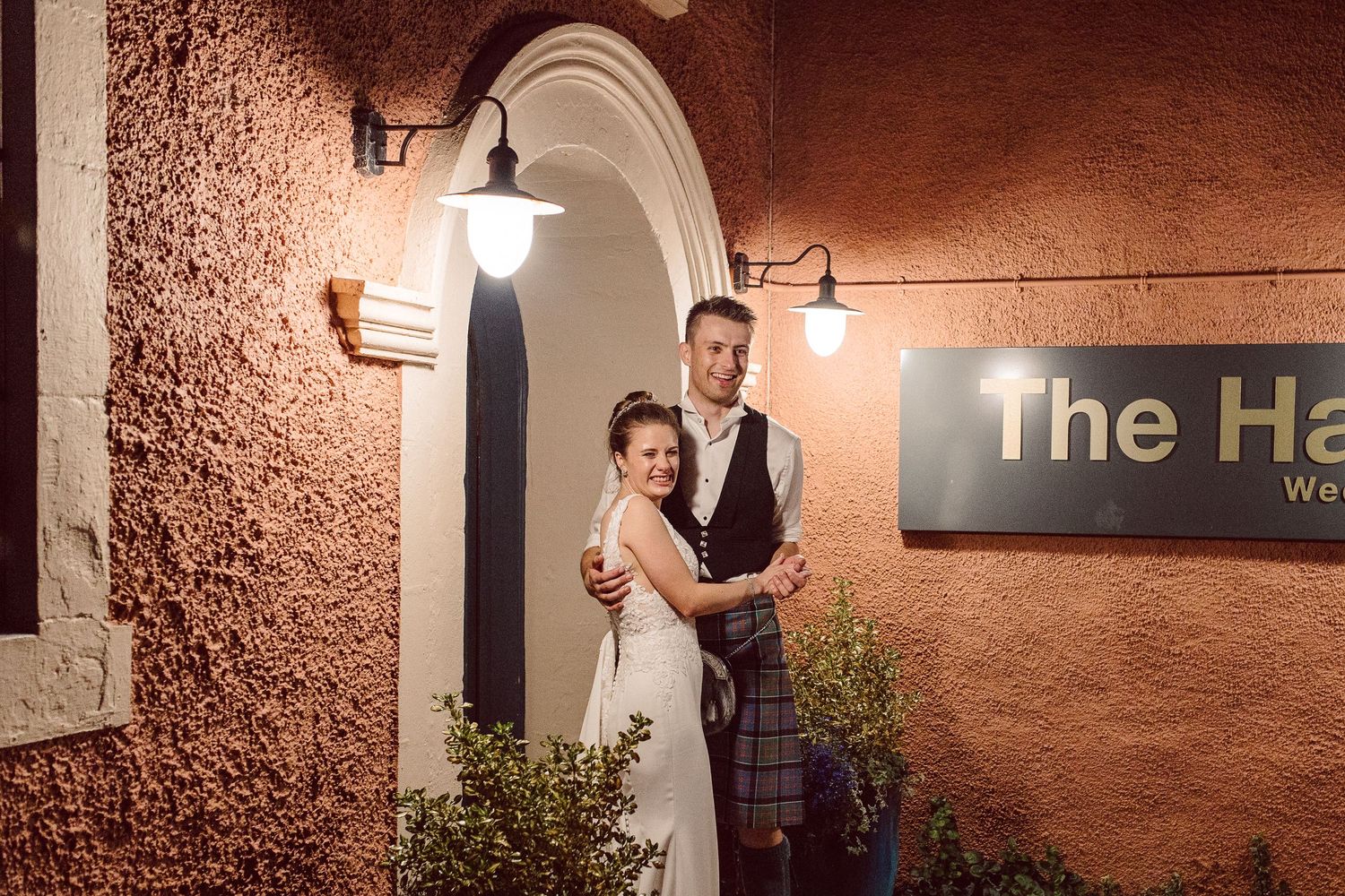 Elegant stone archway entrance with warm lighting and textured walls at The Harp venue.