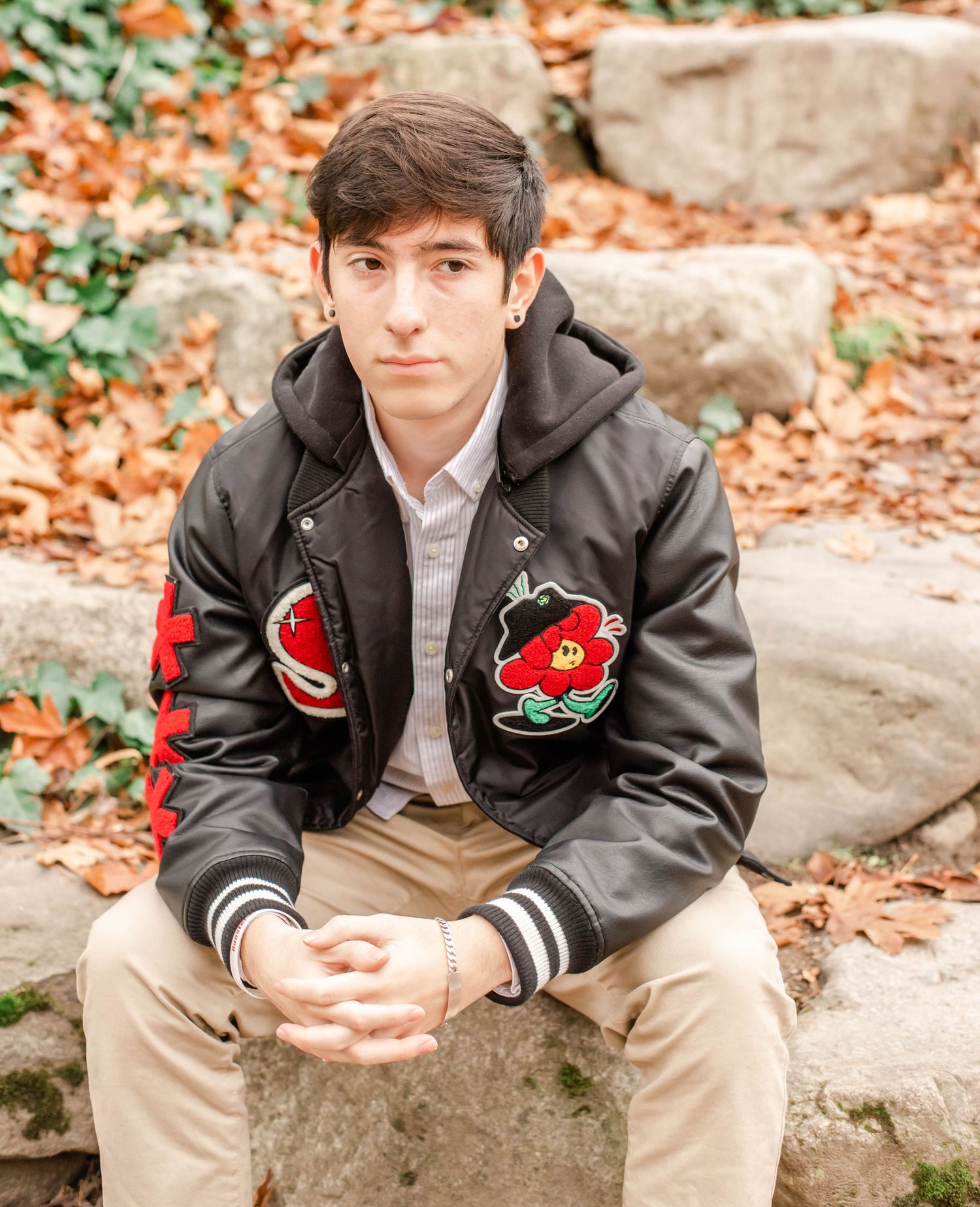 Portrait session on stone steps wearing varsity-style jacket with patches.